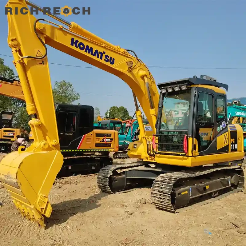 Operator seat and joysticks inside a used Komatsu PC110 excavator cab, low hours, great condition