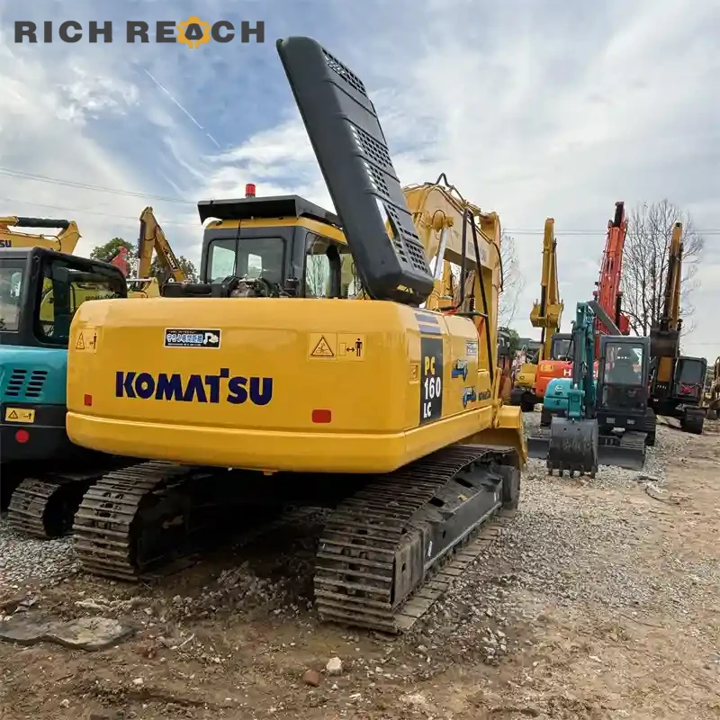 Used Komatsu PC160LC excavator loading a dump truck, digging performance, low hours, stability, priced in USD