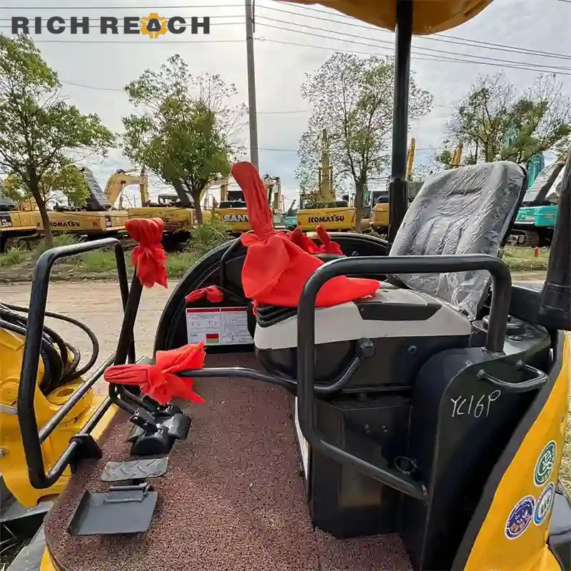 Operator seat and ergonomic joysticks inside a used Komatsu PC35MR mini excavator cab