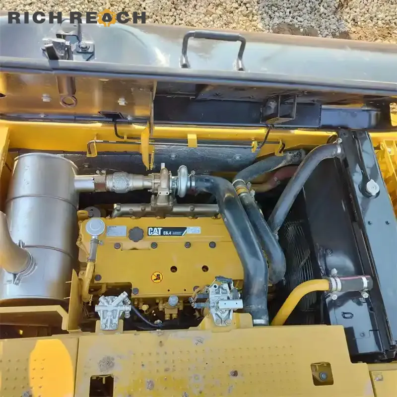 Top-down view of the clean engine compartment on a Caterpillar excavator, highlighting the yellow Cat C6.4 diesel engine, turbocharger, and exhaust system.